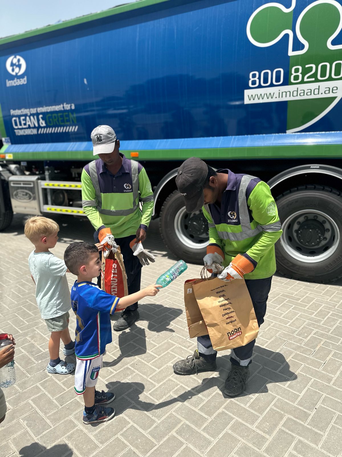 british nursery in dubai Nursery child handing paper waste to recycling team on Earth Day at Remraam branch