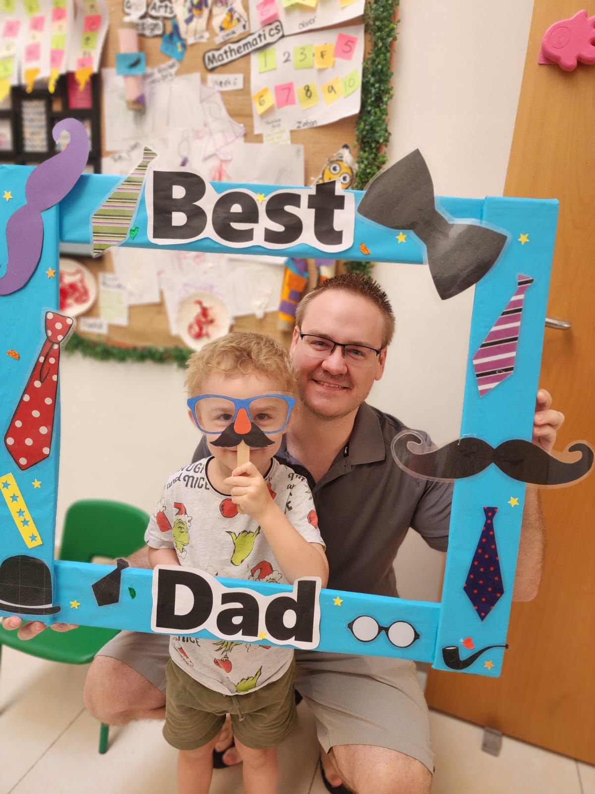 british curriculum nursery in dubai Dad and child posing with a “Best Dad” frame at a British curriculum nursery in Dubai
