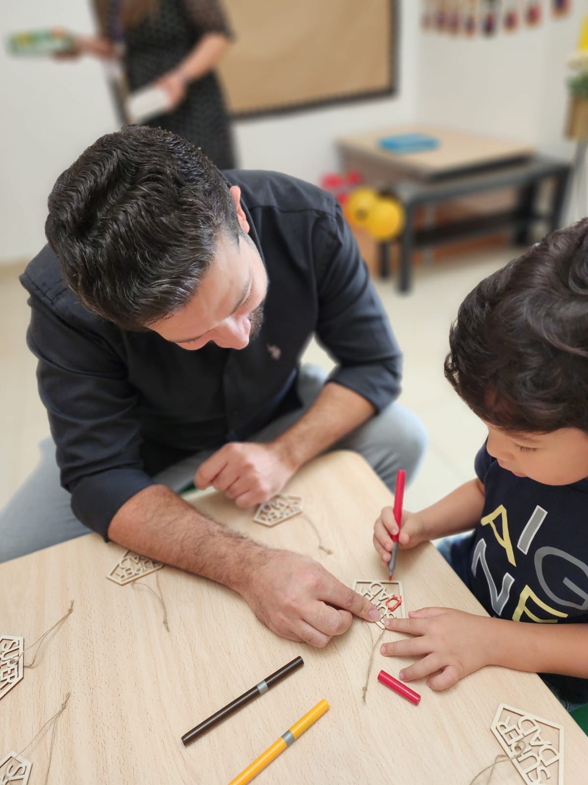 good nursery near me Father supporting his child with a colouring activity at a good nursery near me